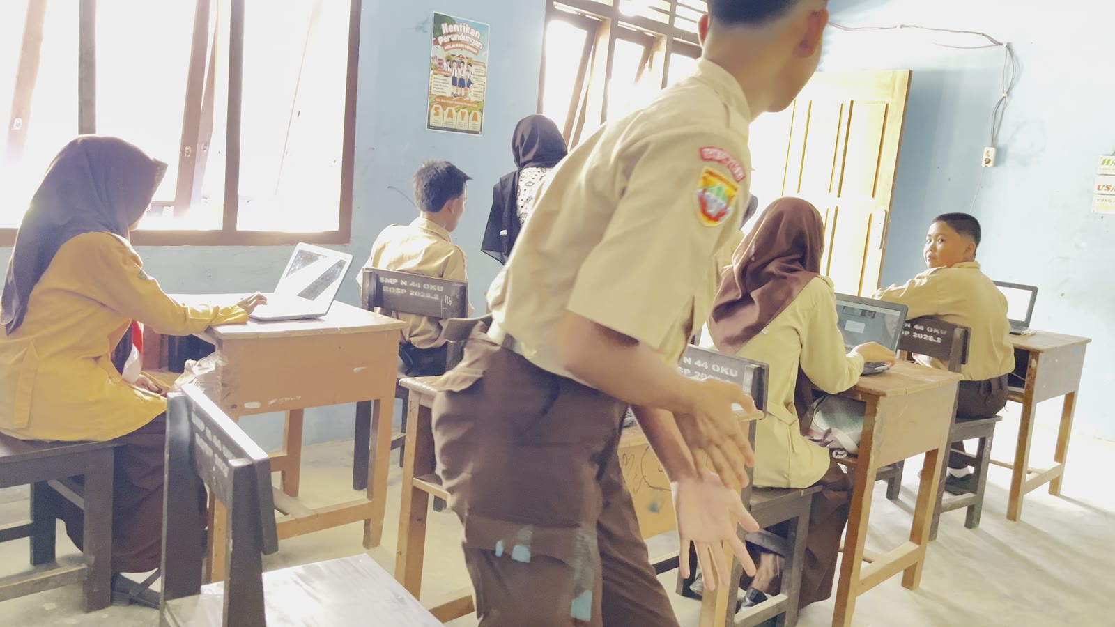 Guru mendampingi peserta didik belajar menggunakan komputer di kelas